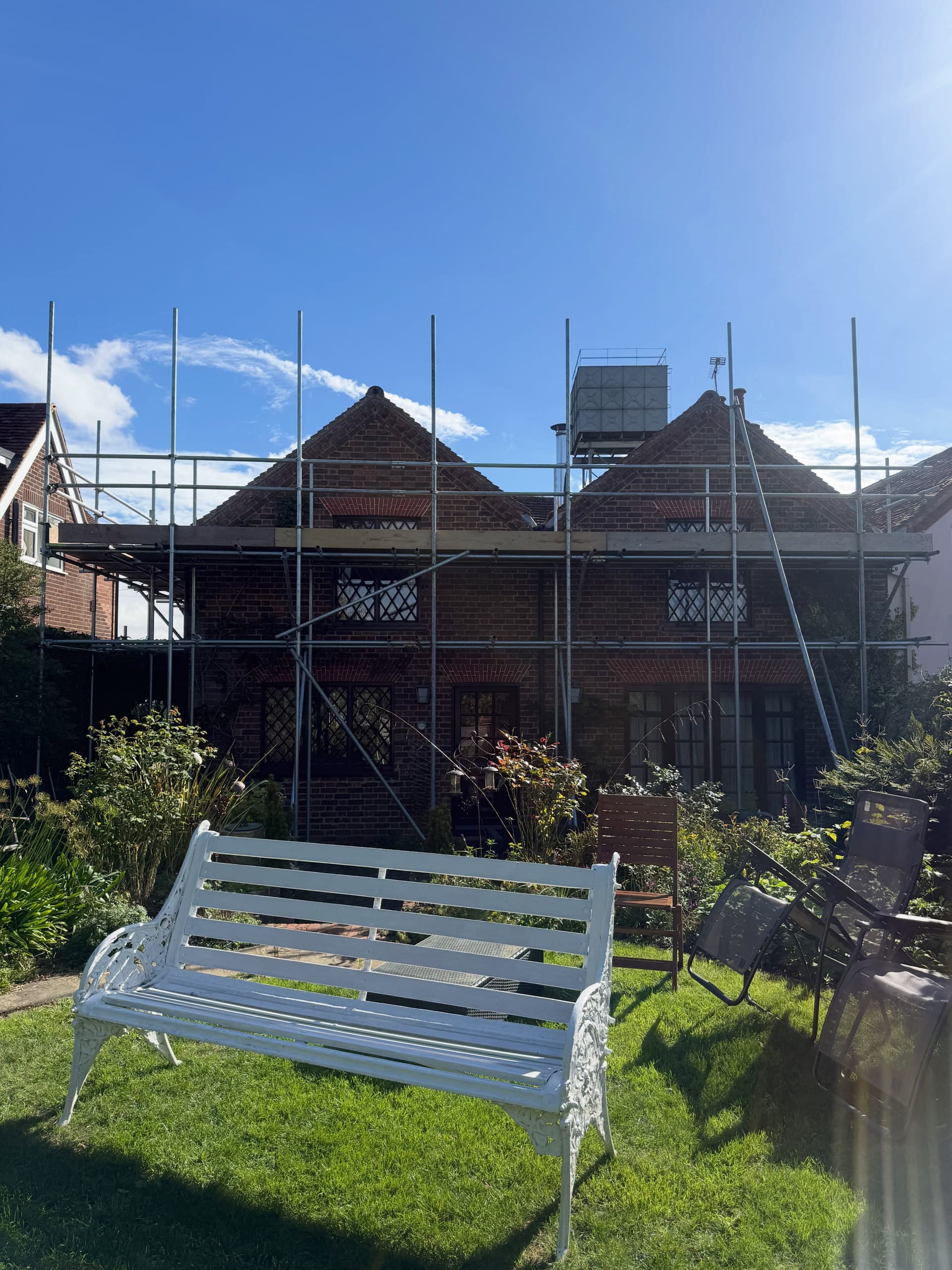Cottage with full scaffold seen across a garden