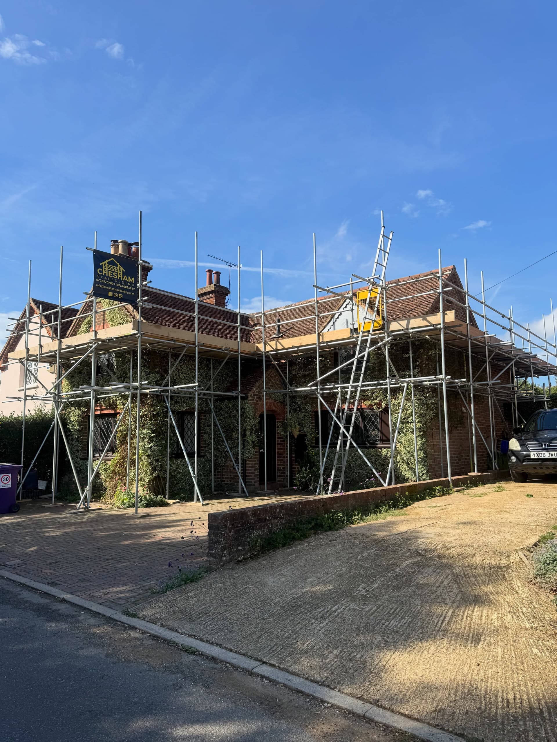 Cottage with scaffold on two sides, ladder access and a company board