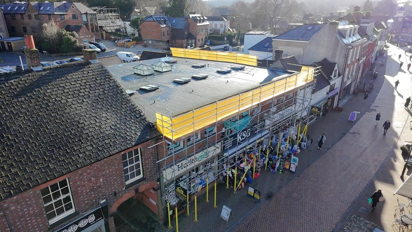 Drone view of a high street shop with scaffold, yellow fans and a protected walkway