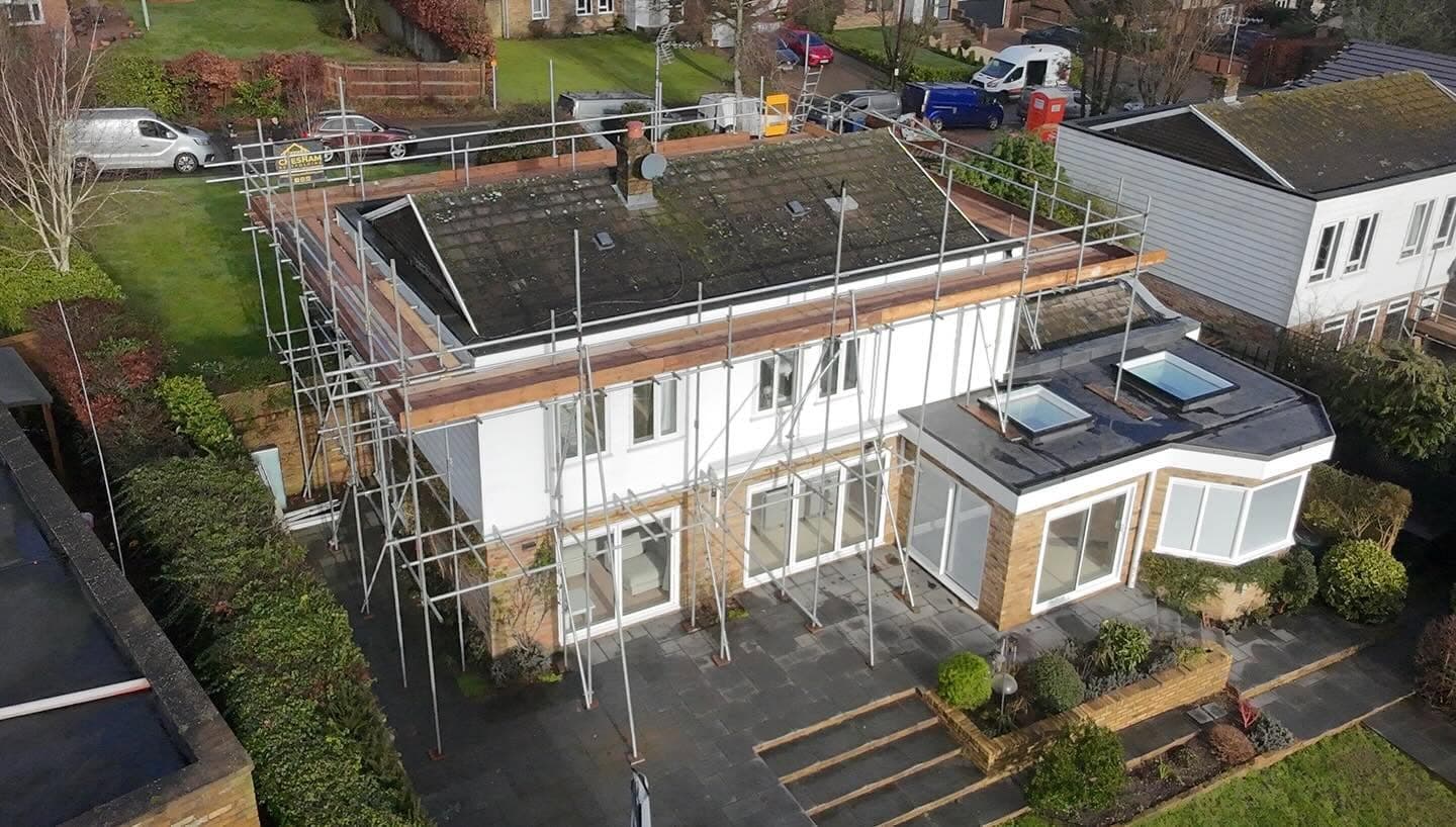 Drone view of a detached house with full scaffold beside a kitchen extension