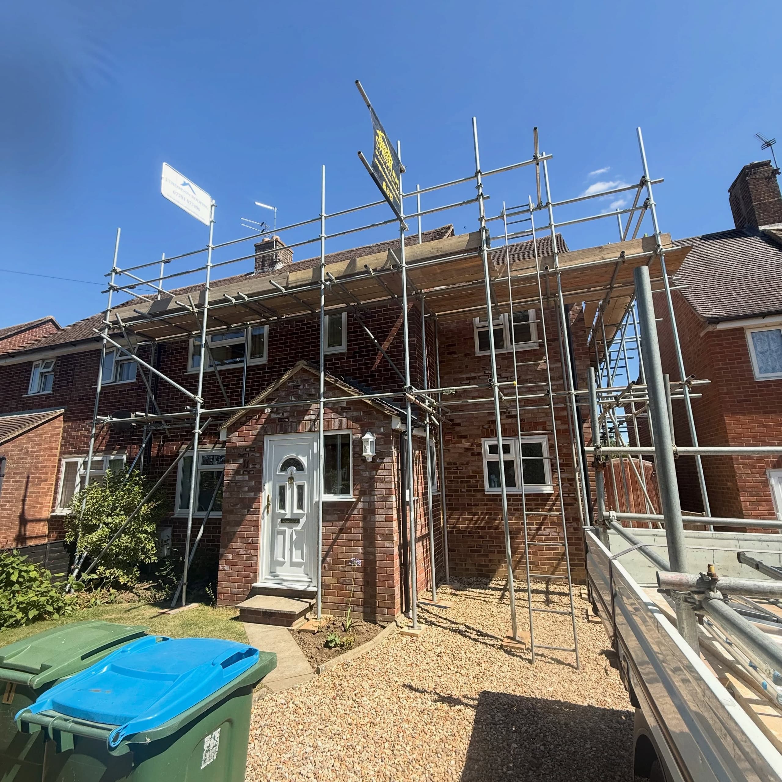 Semi-detached house with scaffold, tubes still on the lorry in front