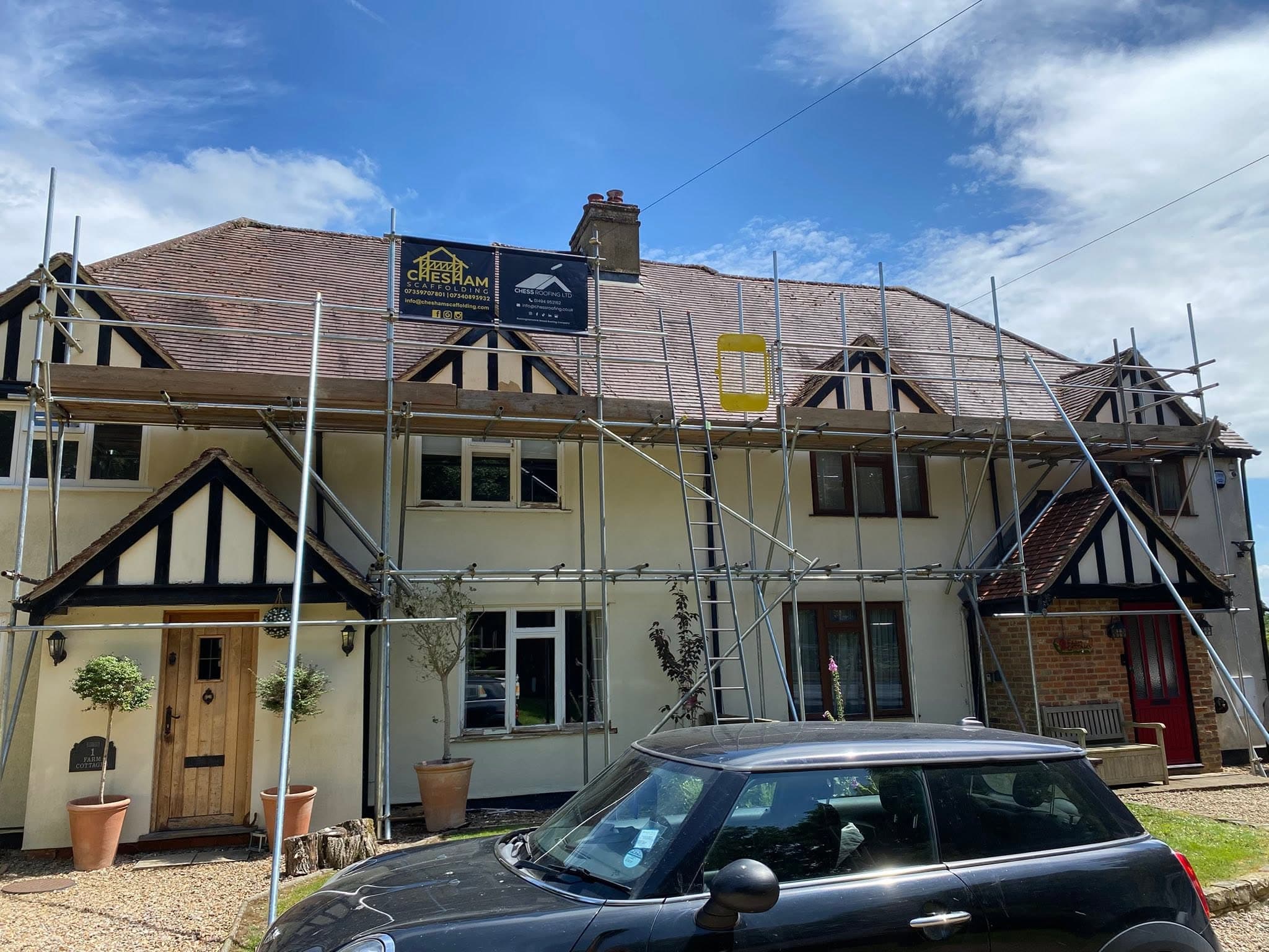 Mock-Tudor terrace with full-width scaffold and two boards