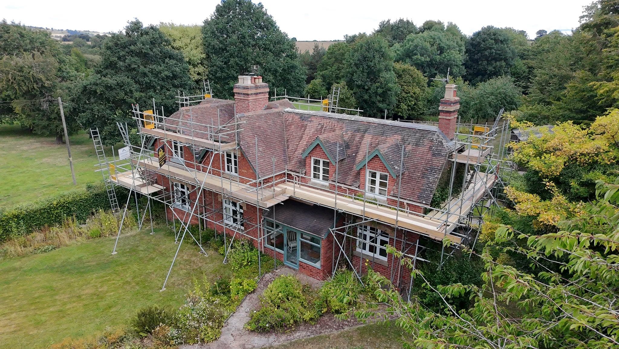 Drone view of a Victorian red-brick house wrapped in scaffold