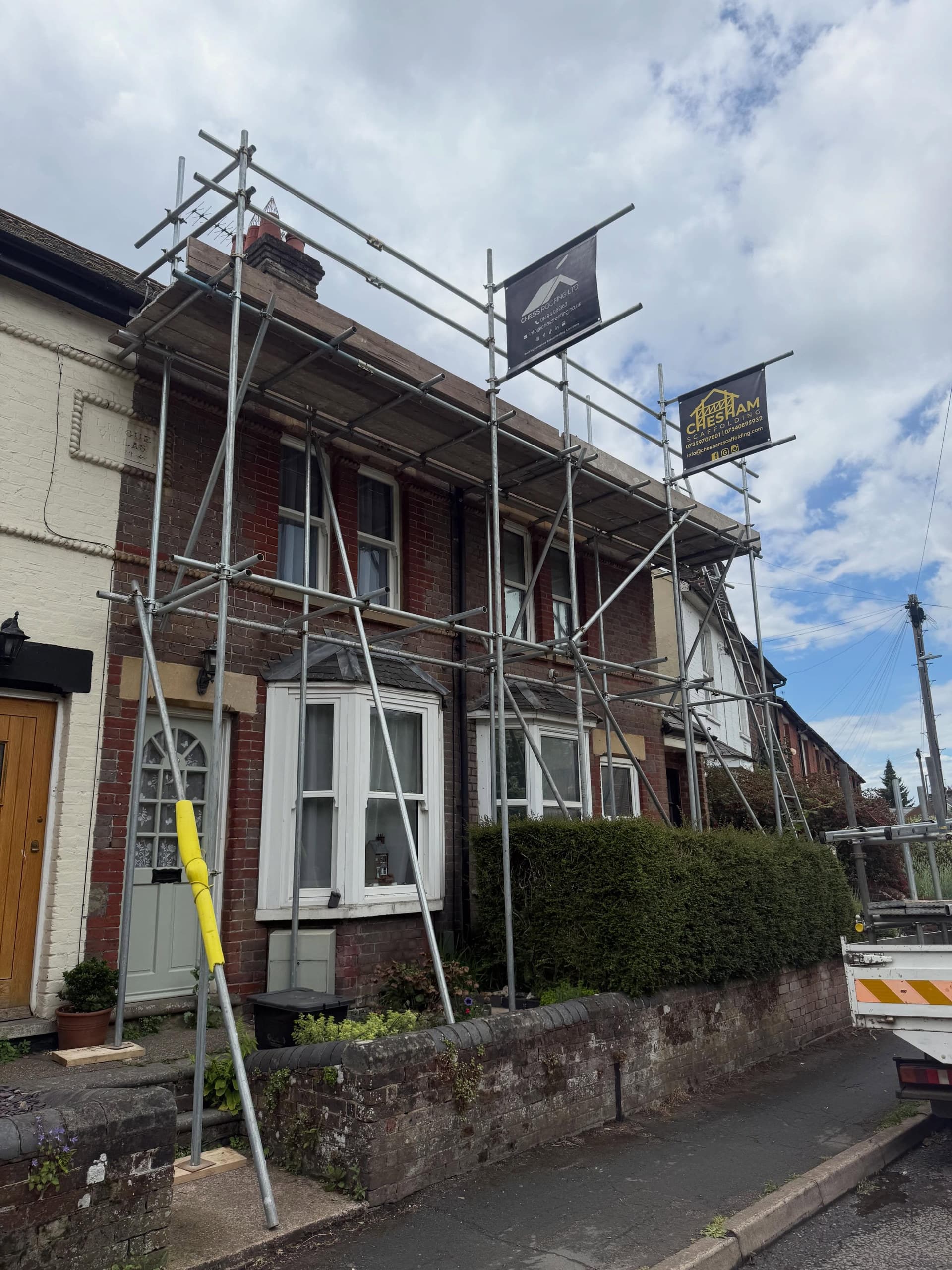 Victorian terrace with front scaffold and two boards on a sloping street